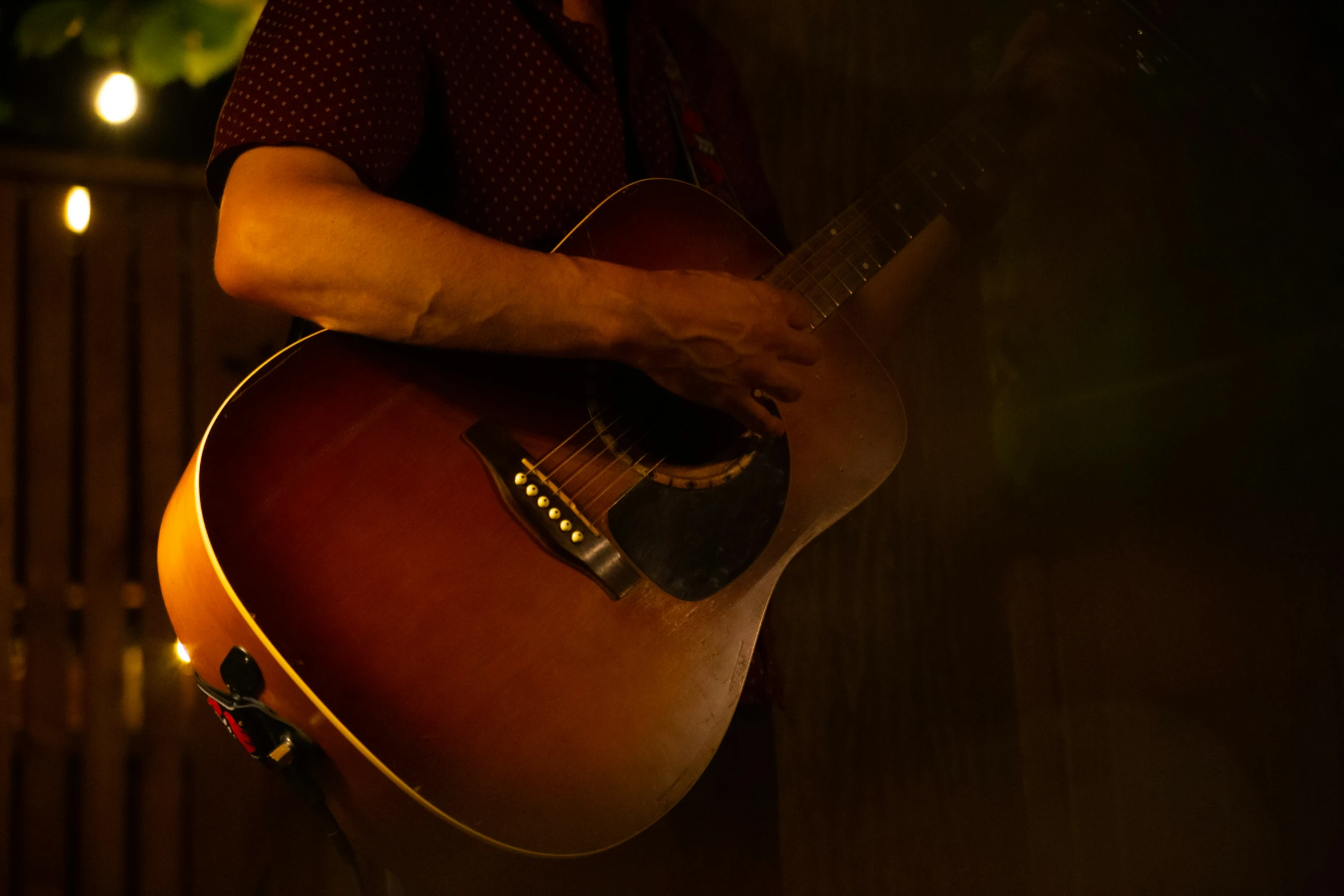 a person standing by a fence playing an acoustic guitar