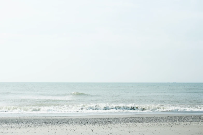 an ocean view with an empty beach and wave coming in