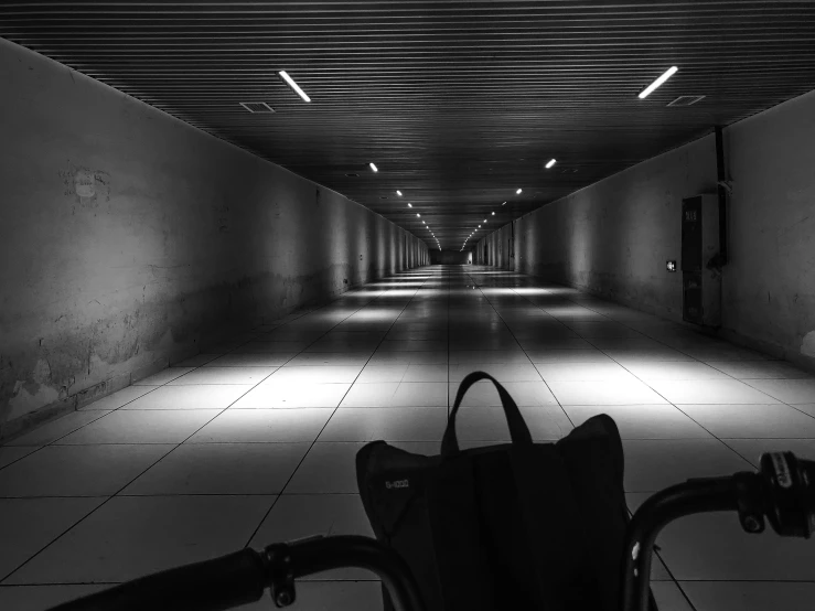 an empty walkway that has light from the ceiling