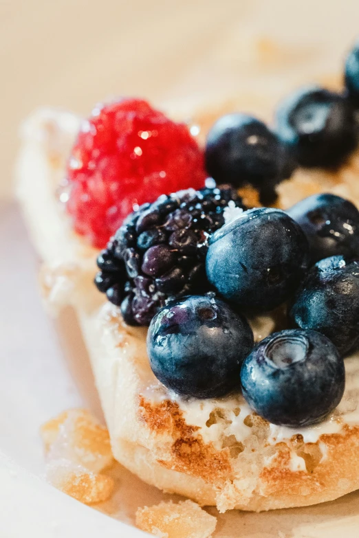 a toasted pastry has blueberries, strawberries and jam on it