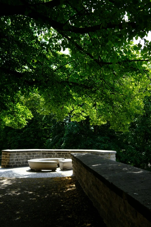 there is an empty stone bench in the shade