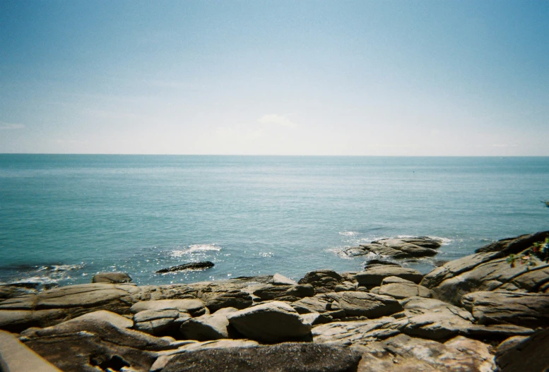 an ocean is seen with rocks and blue skies
