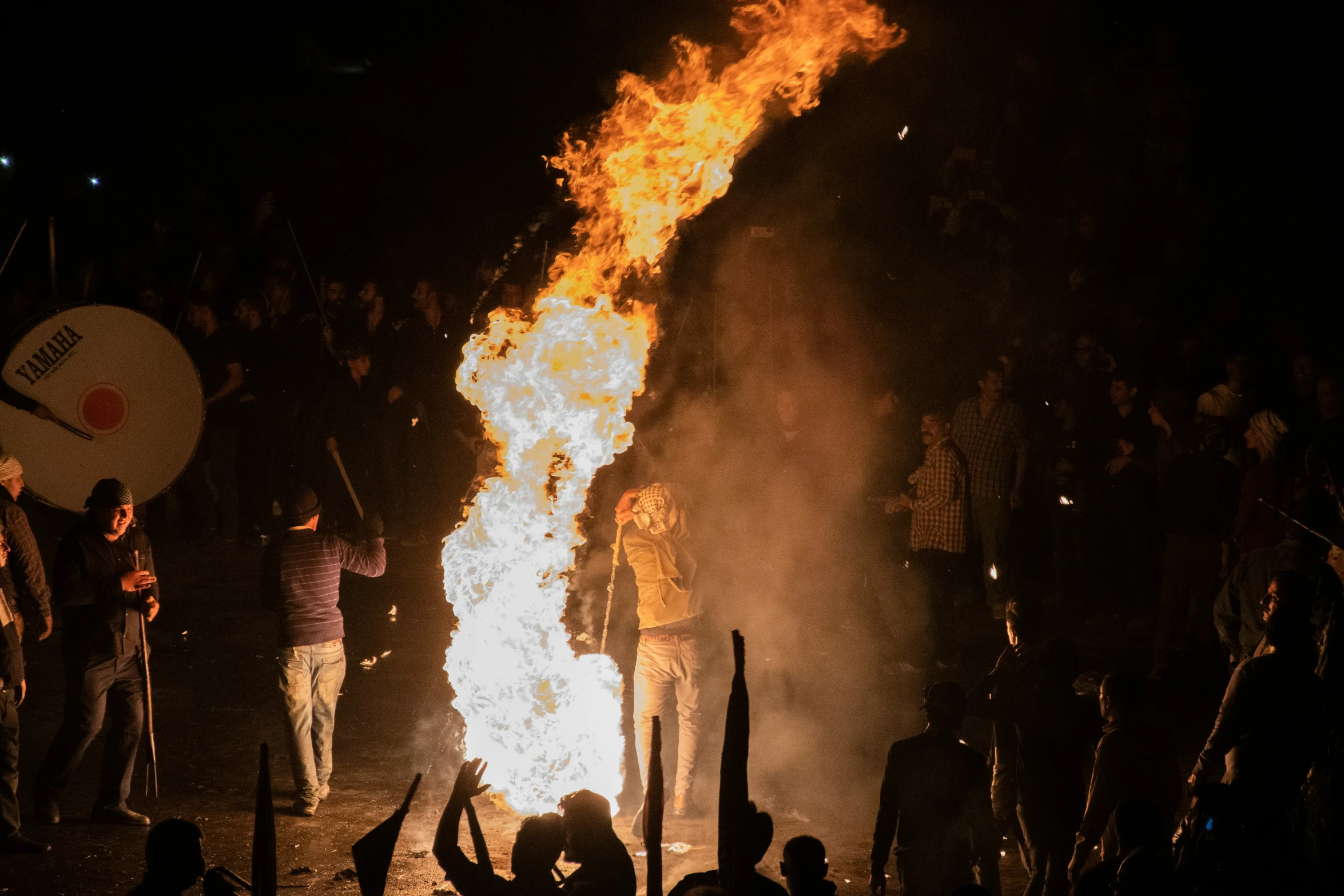 people standing around a fire pit at night