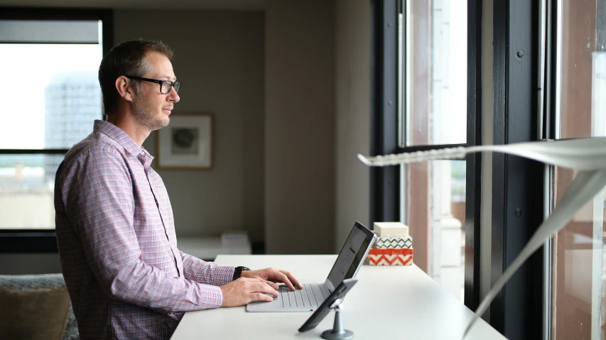 a man with glasses using a laptop on a table