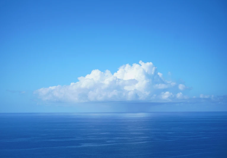 the sky is cloudy and blue above an ocean