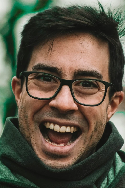 a man with glasses and a goatee in front of a green background