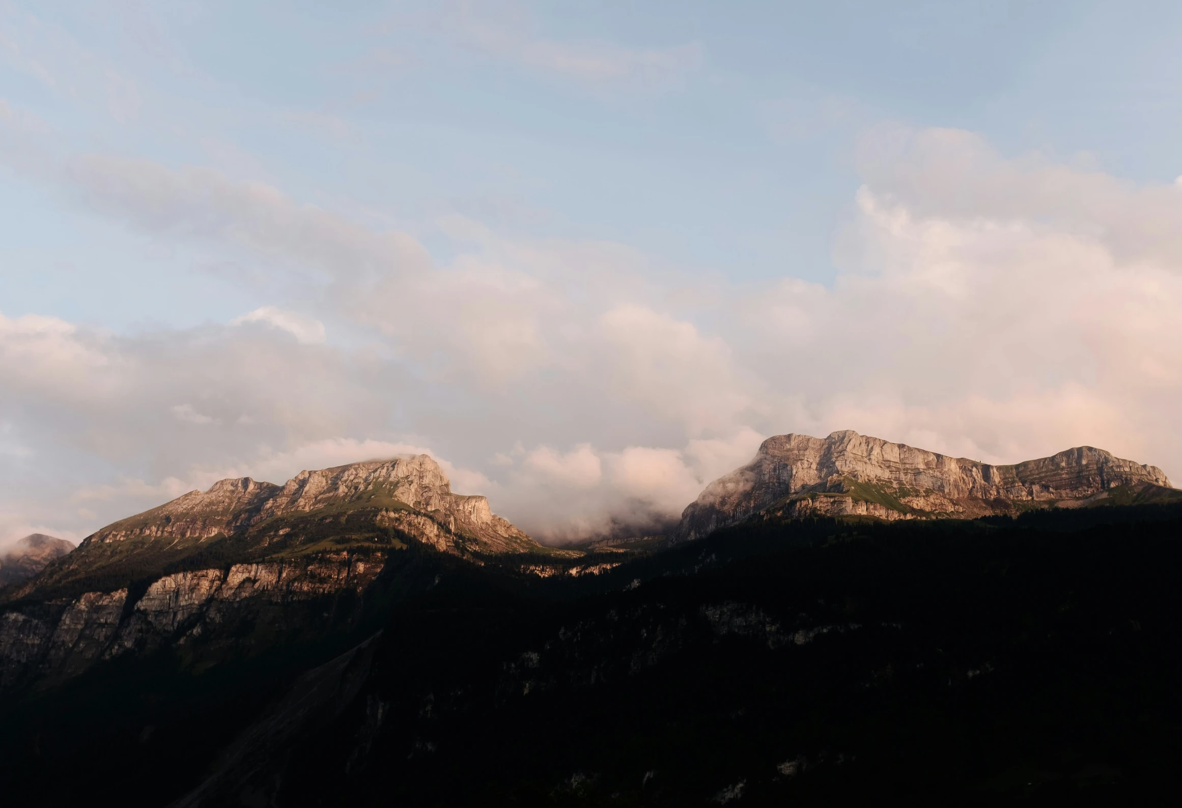 mountains covered in clouds beneath a blue sky