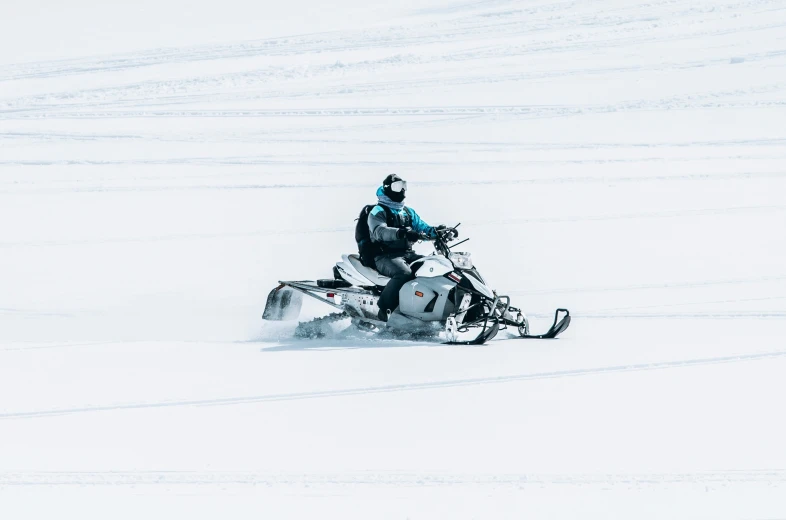 a person on a snowmobile rides through the snowy field