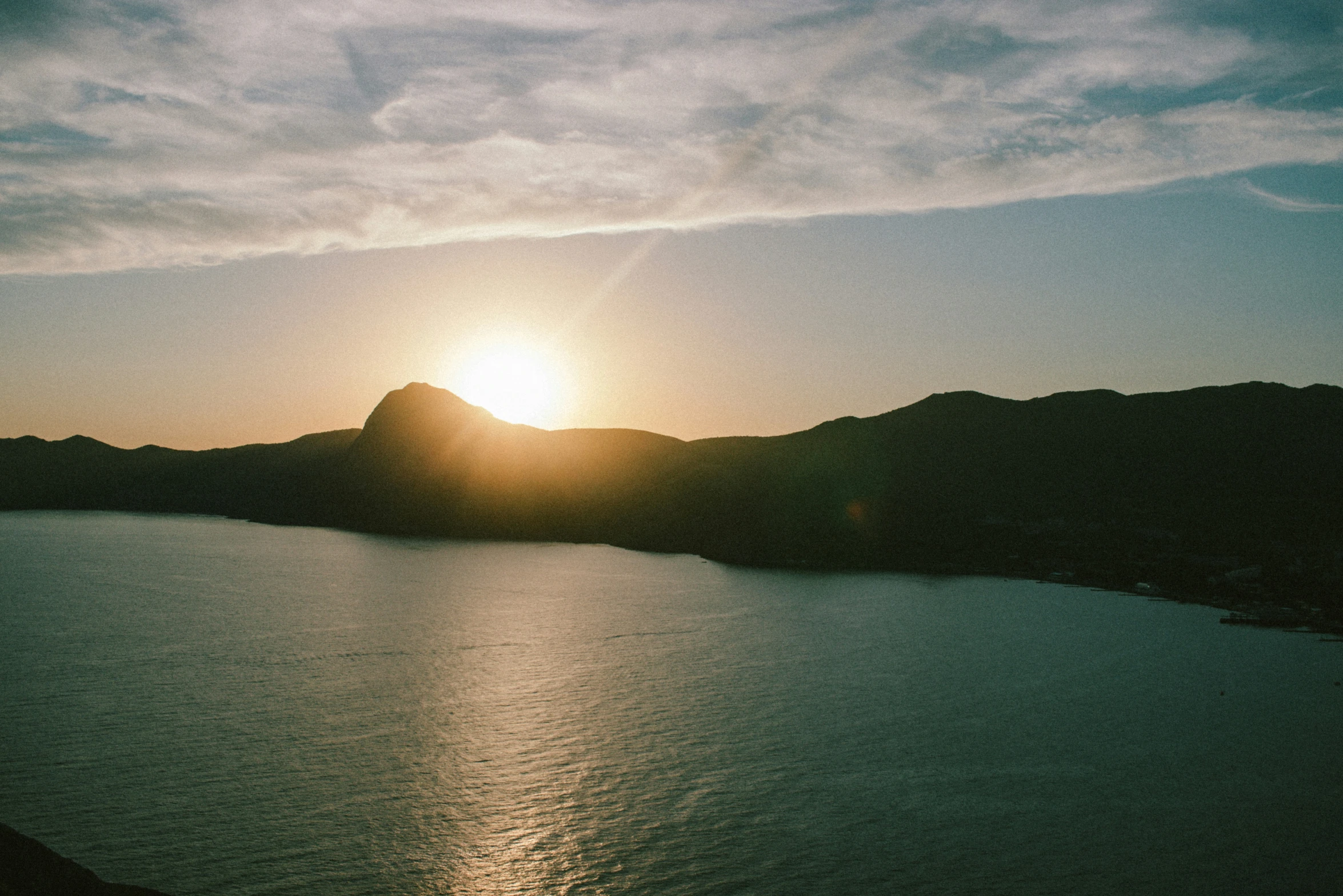 the sun shining through the clouds over water