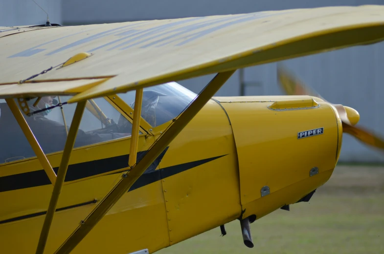a yellow biplane parked next to a wall