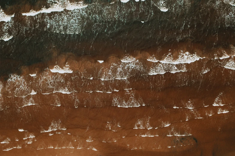 a brown beach with white surf and water