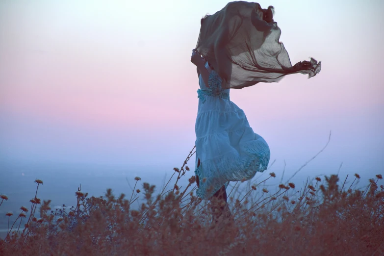 a woman is in a white dress standing on a hill