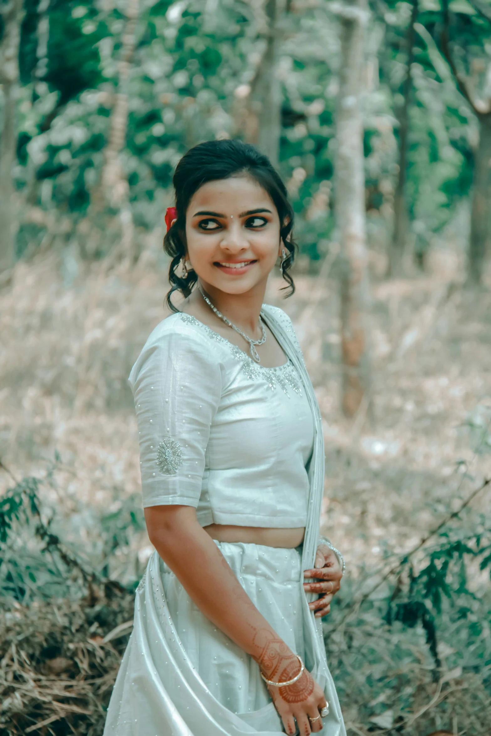 a beautiful woman standing in front of a forest