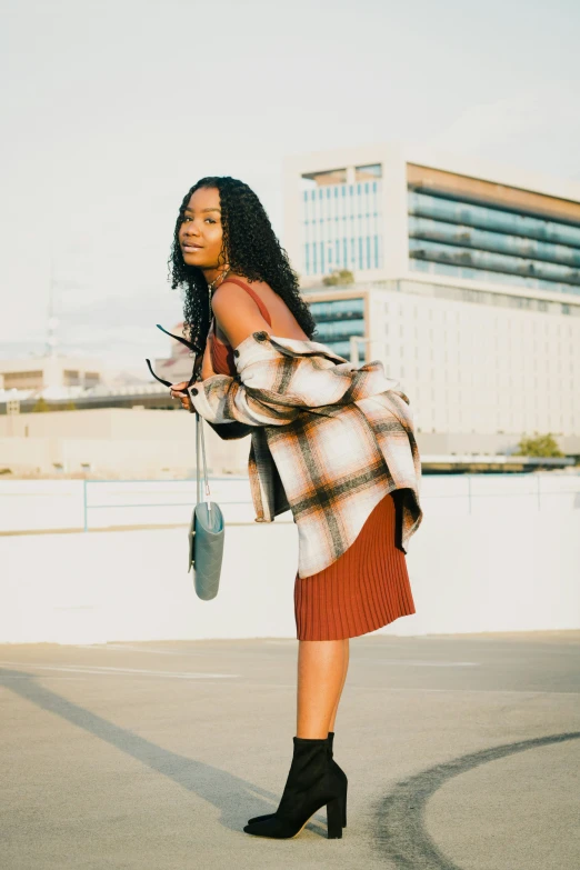 woman with glasses and coat posing on top of a roof