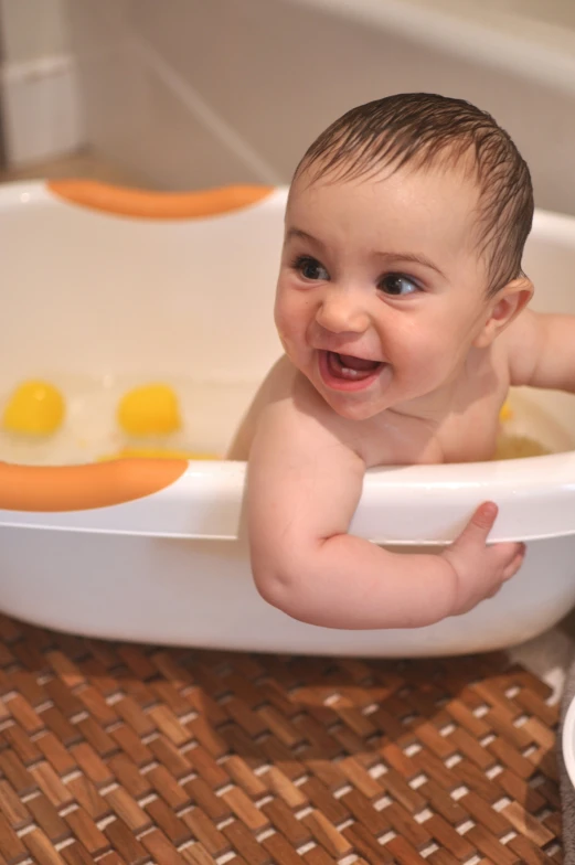 an infant in a tub laughing while sitting