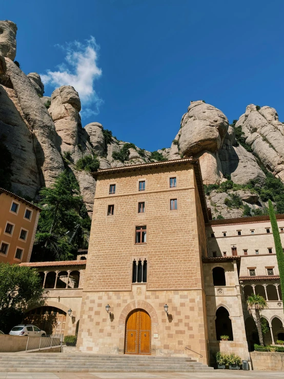 a stone castle sitting between two mountains under a blue sky