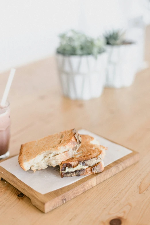 a plate with a sandwich next to a container of chocolate milk