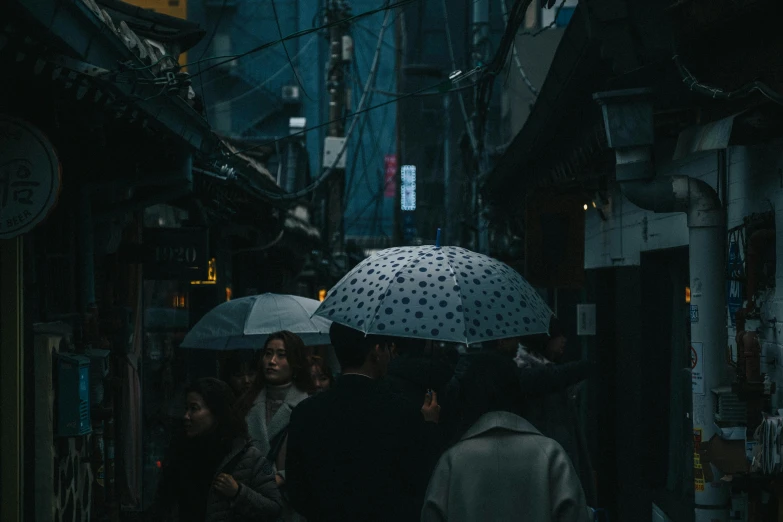 some people holding umbrellas in an alley
