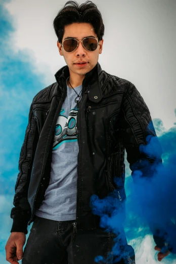 man standing on blue cloud of smoke with black leather jacket