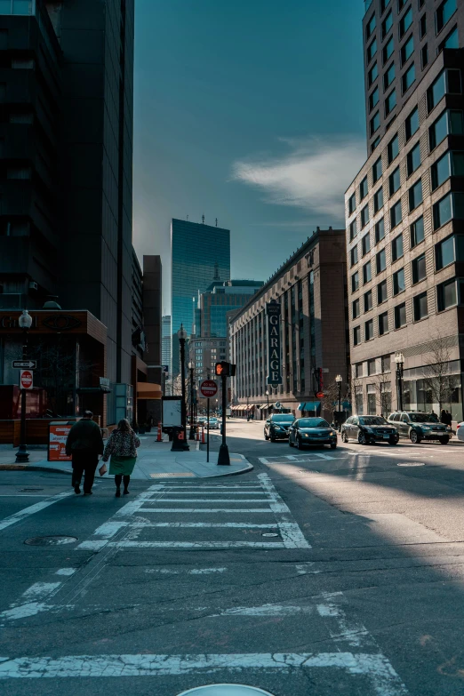 an empty city street with cars stopped at the corner