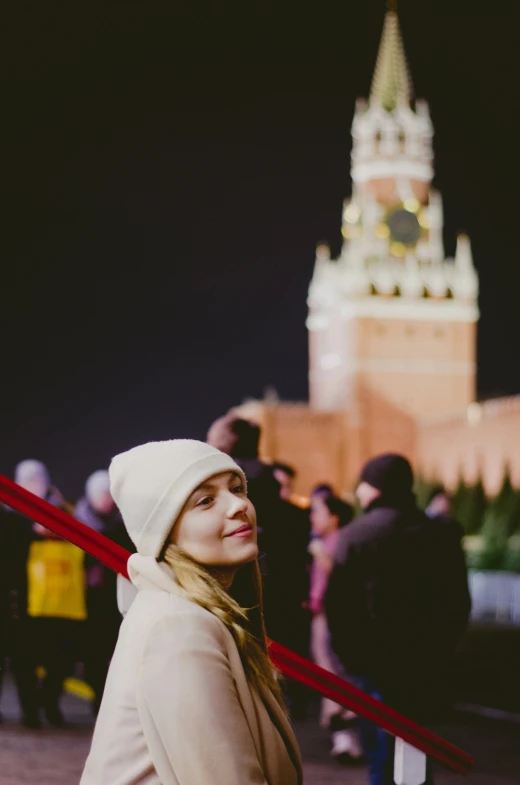 woman in winter hat looking out at castle with people