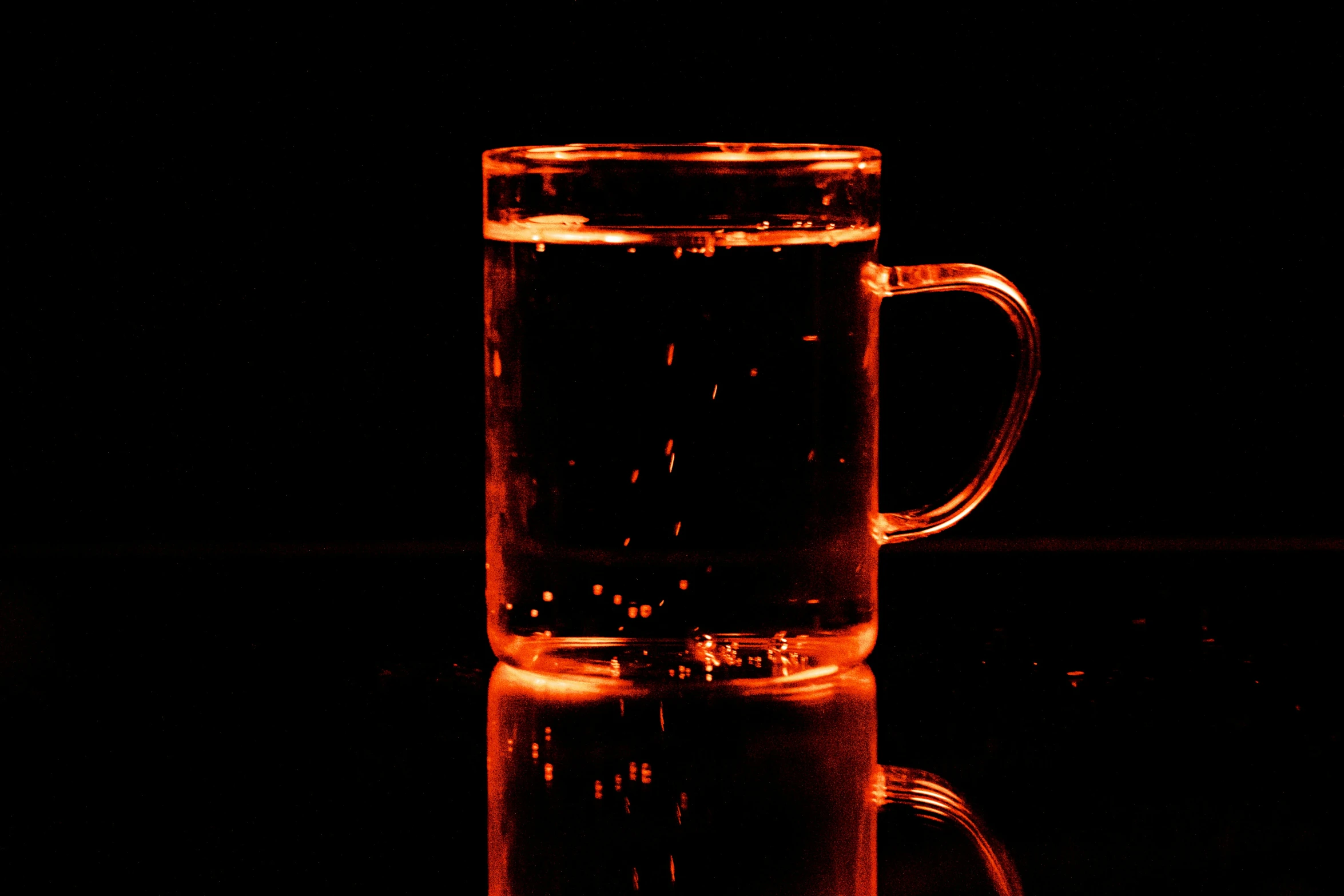 a glass cup on a table is lit up in the dark
