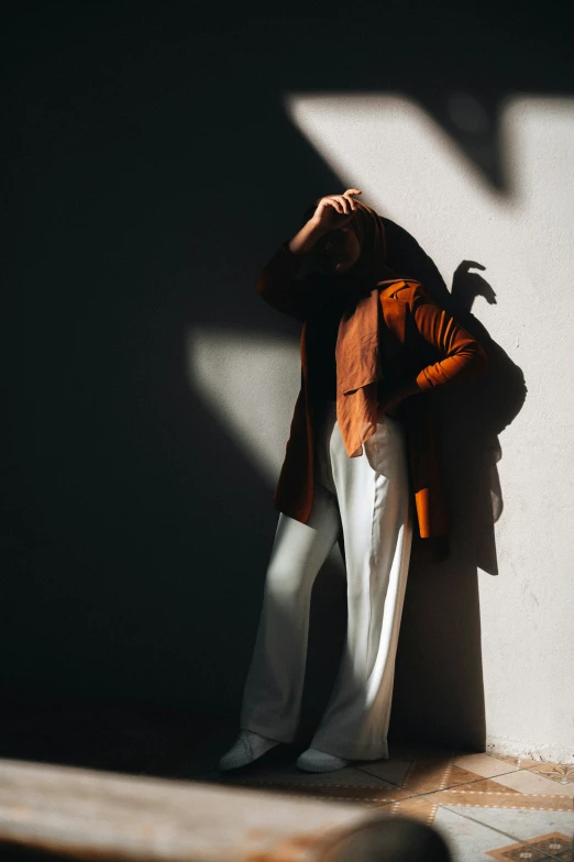 a woman with her hand on her head posing against a wall