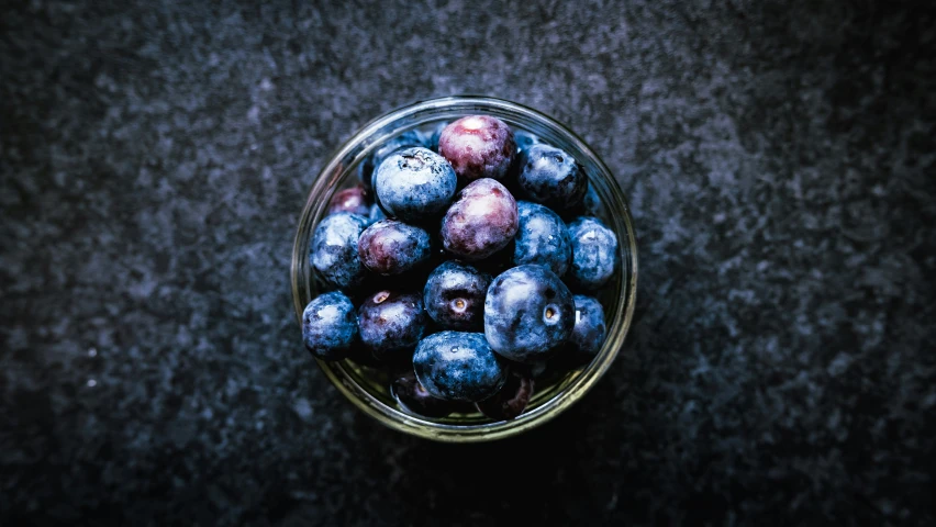 a glass bowl full of blueberries on a table