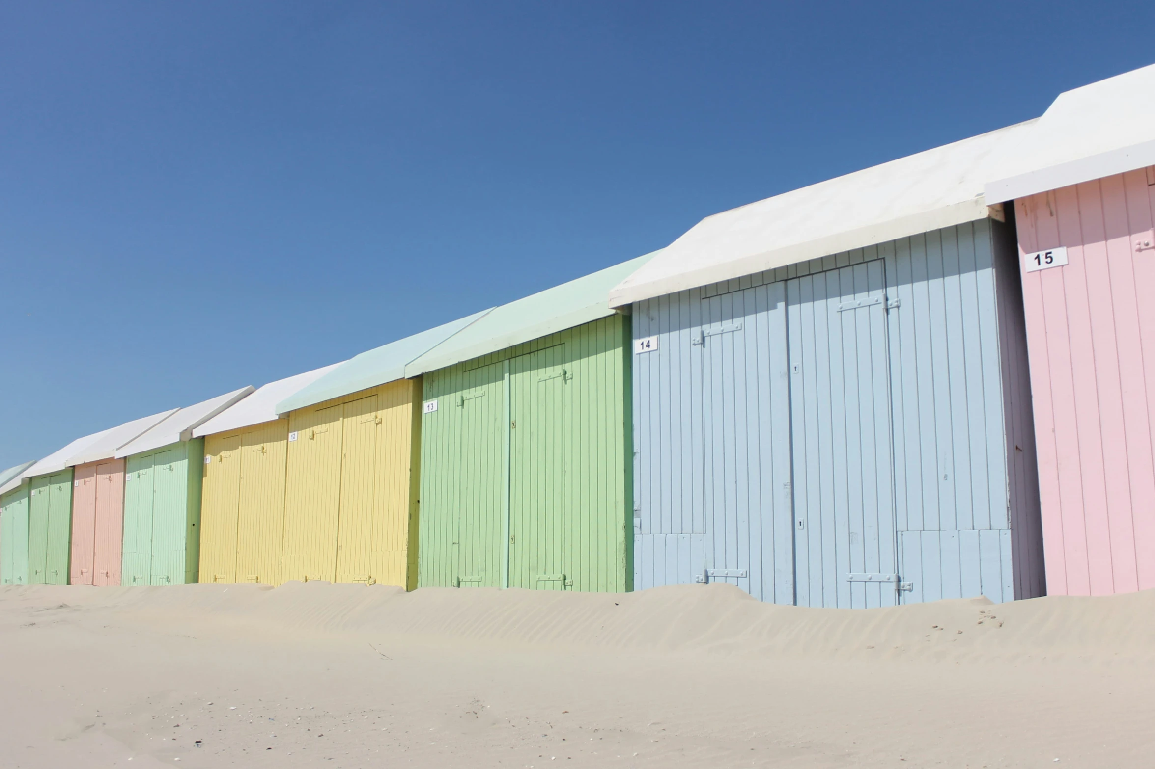 a row of multicolored wooden buildings in the sand