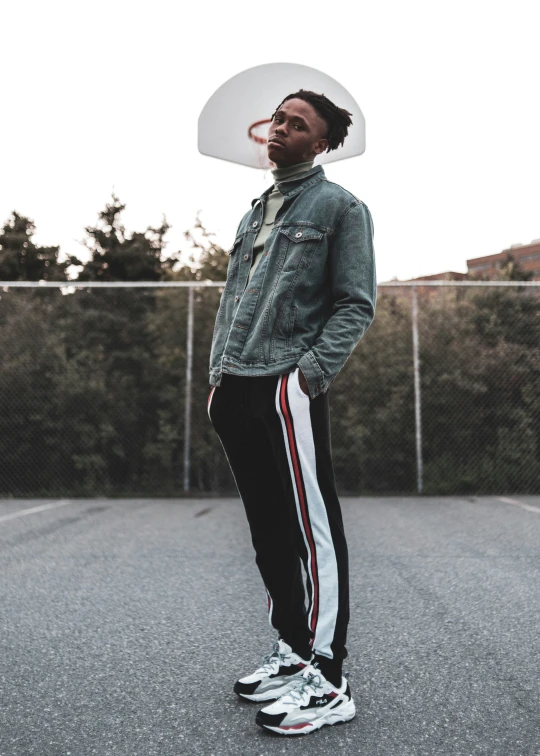 a man in a denim jacket stands on an outdoor court