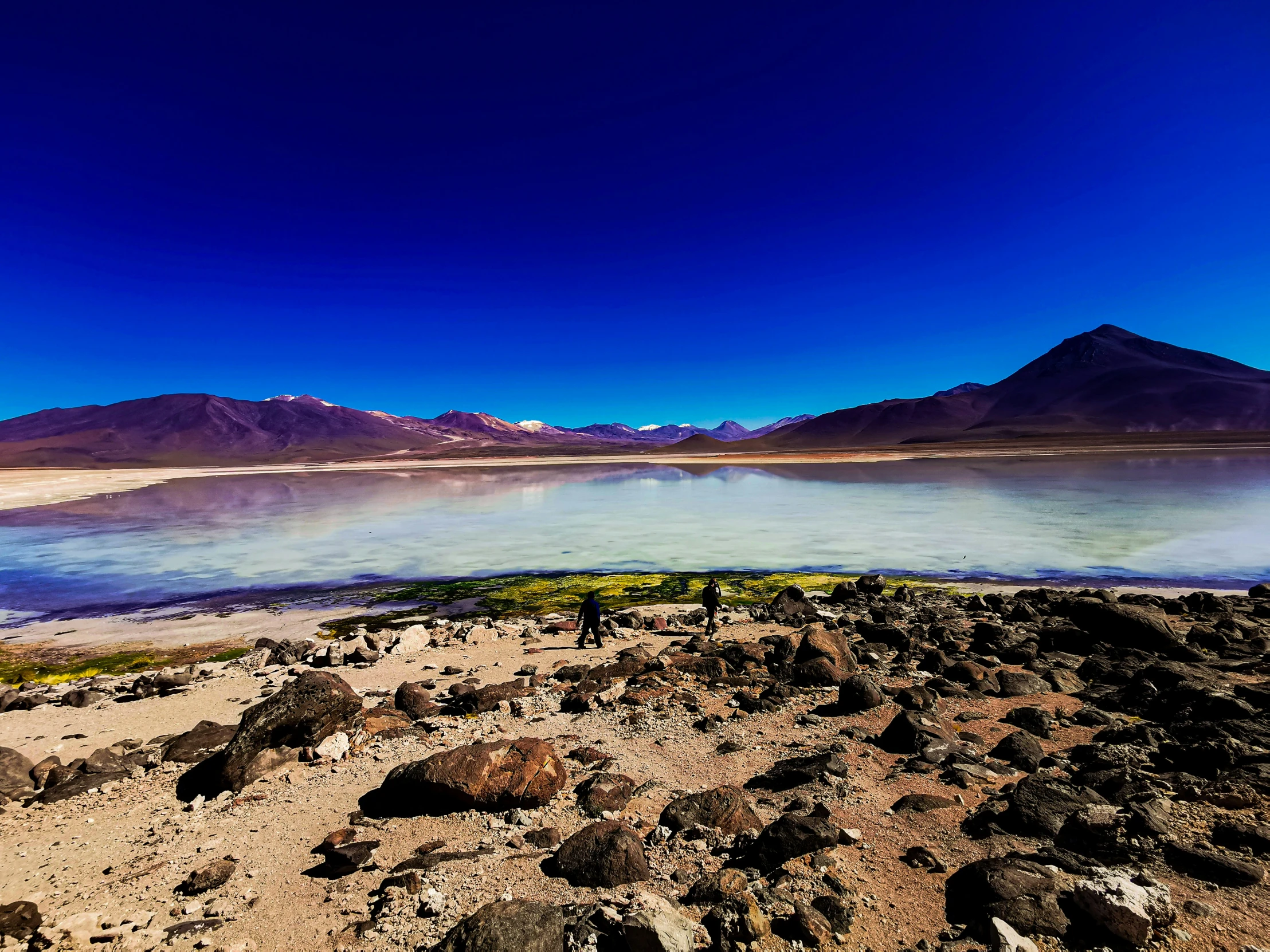 a rocky area with water and large mountains in the distance