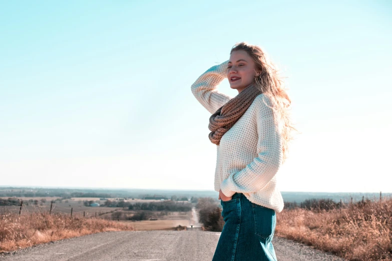 a young woman stands in the middle of an empty road