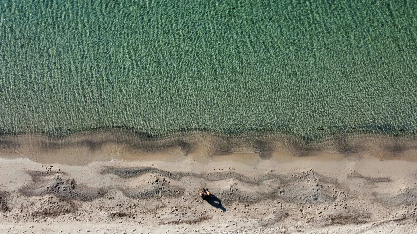 a man is on the sand looking at the water