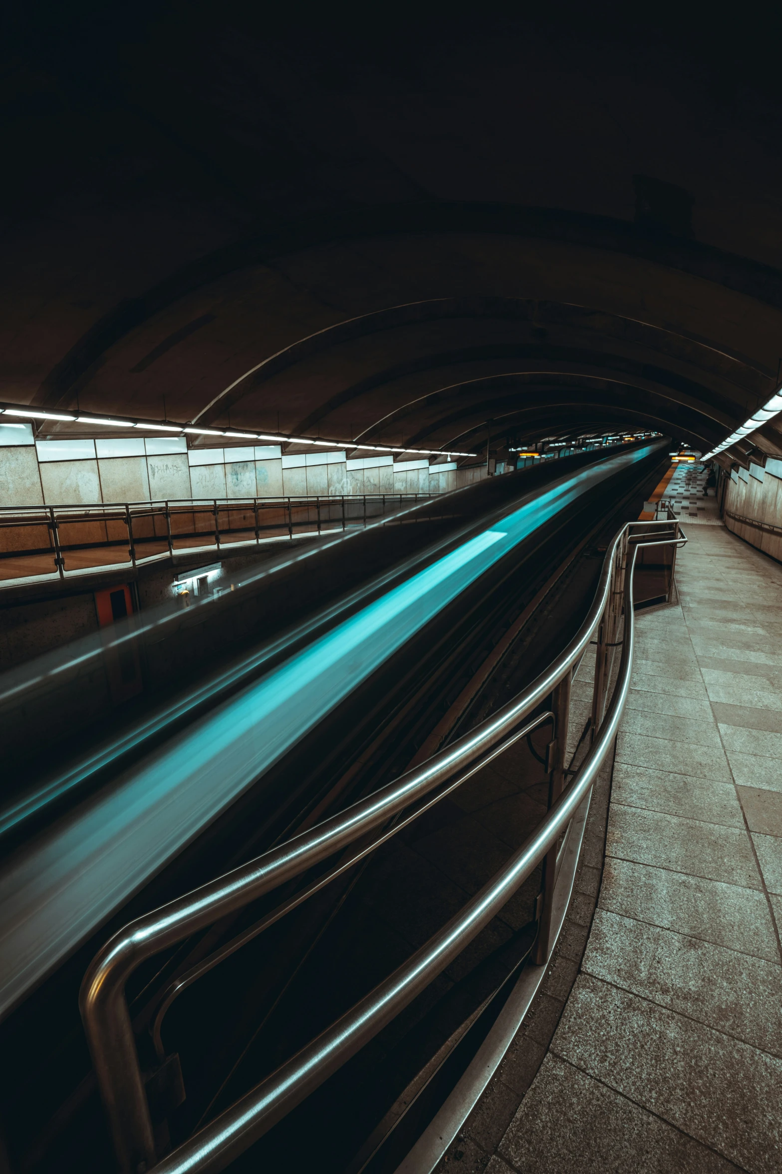 a large tunnel with metal railings next to an exit way