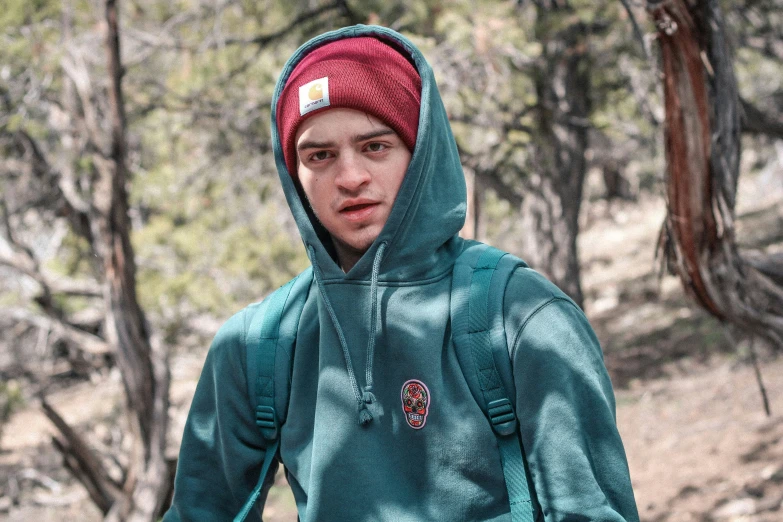 a young man wearing a green jacket and red cap