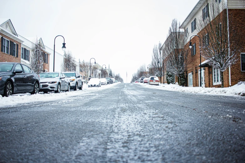 the street is covered with snow and parked cars