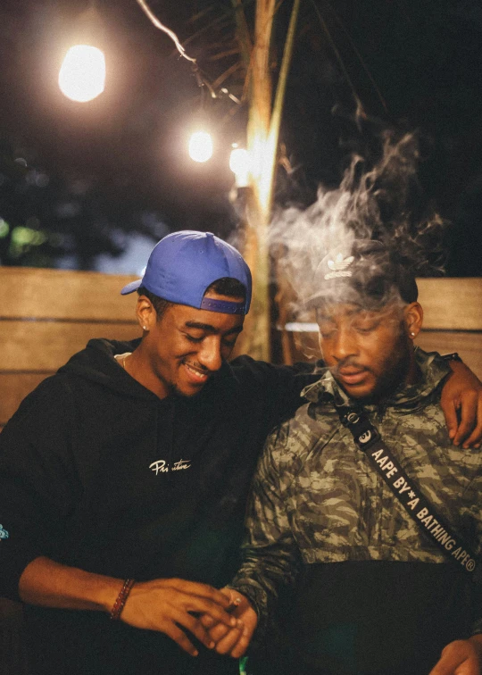 two men smoking electronic cigarettes on a bench