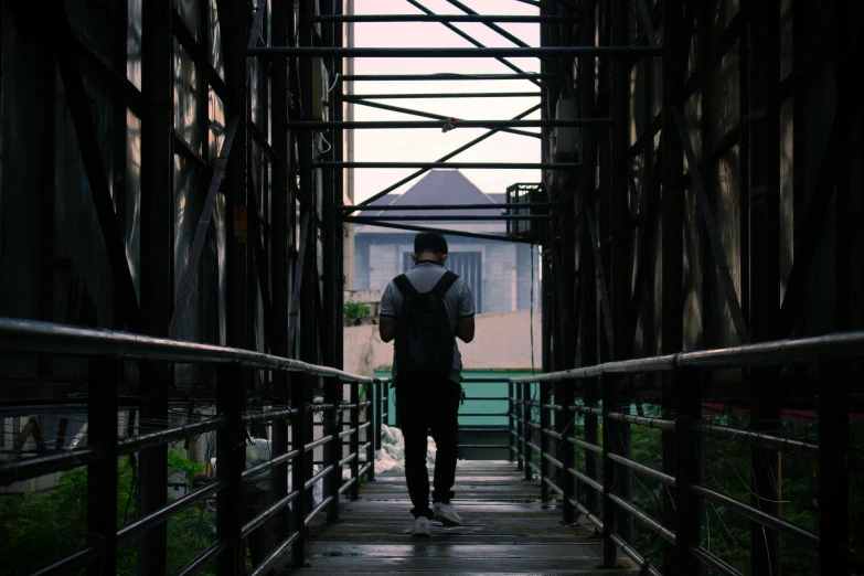 man walking down a pathway over a bridge at dusk