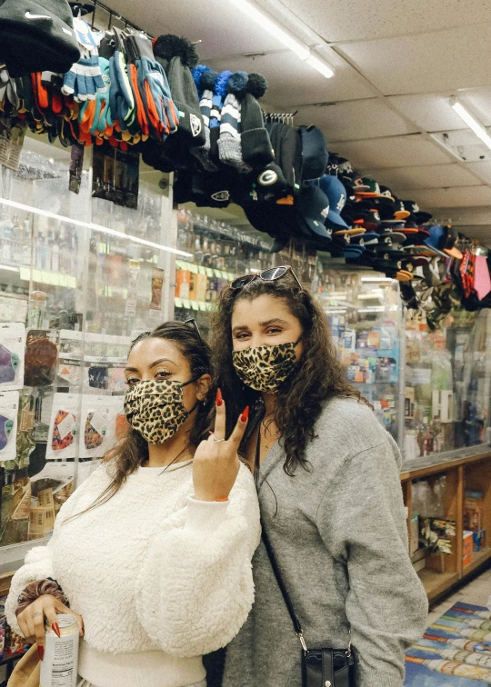 two women pose with face coverings on each face
