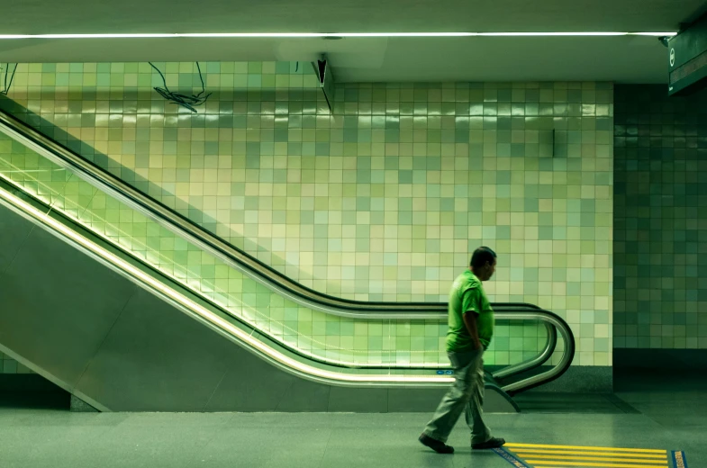 a man in a green shirt is going down an escalator