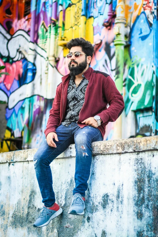 a man sitting on top of a cement wall next to graffiti