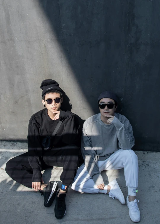 two women pose for a po while sitting on the sidewalk