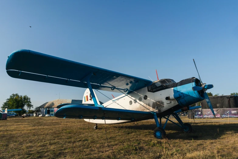 a blue and white biplane sitting in a field