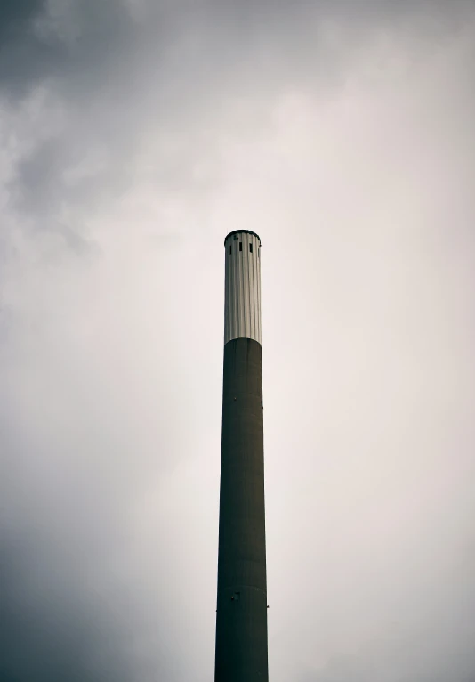 a tall industrial chimney and clock in an industrial setting