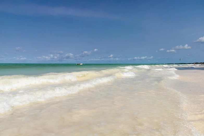 a very pretty beach and some water with boats in the distance