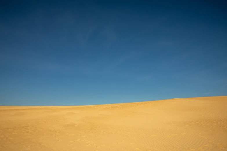 a woman is walking through the sand dunes