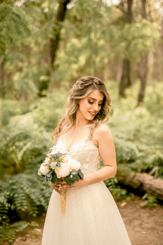a woman wearing a white wedding dress standing in the woods