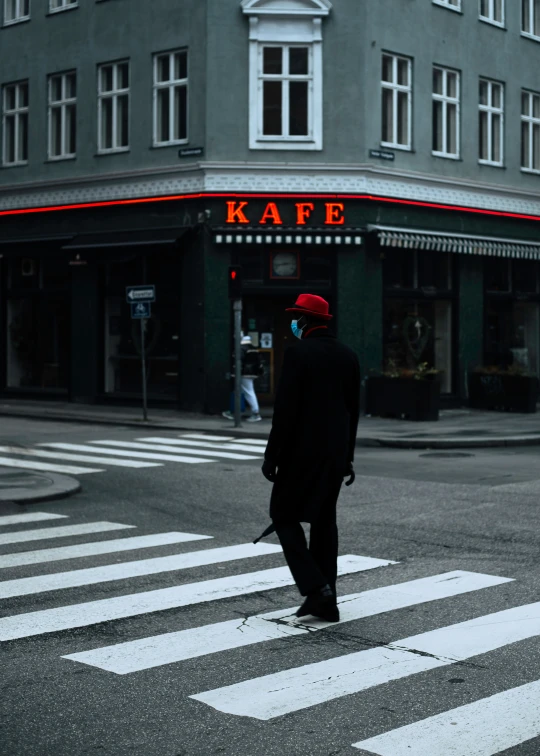 a man crossing the street in front of a kafe