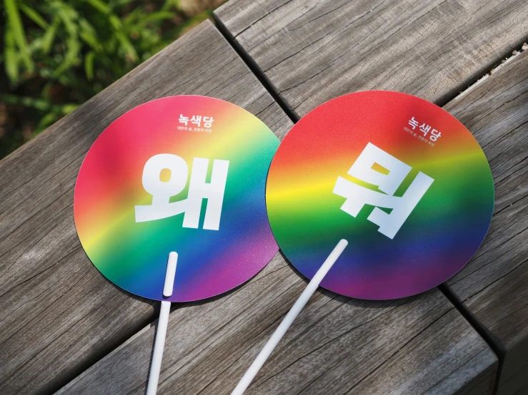 colorful fans on stick by wooden bench near plants