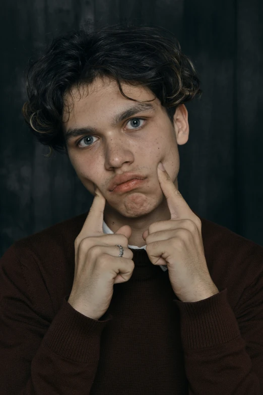 a man with his finger in front of his face and fingers under his nose